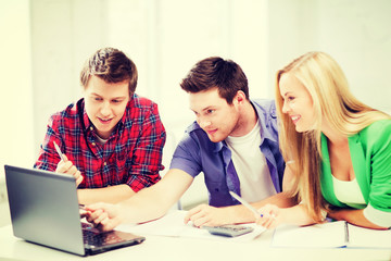 Fototapeta premium smiling students looking at laptop at school
