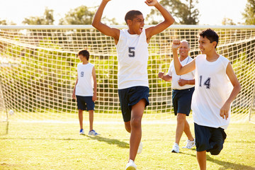 Player Scoring Goal In High School Soccer Match
