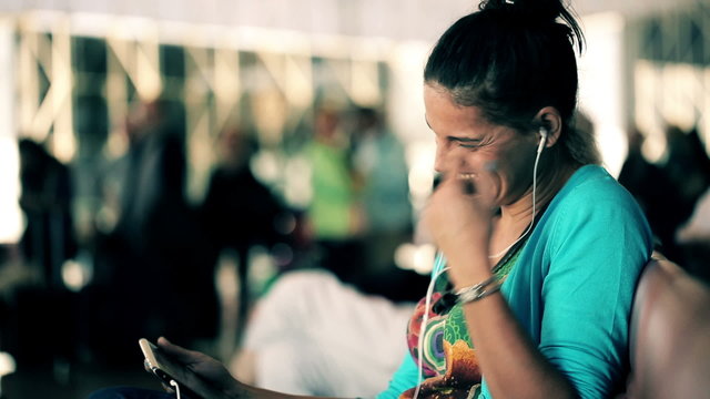 Young woman watching funny film on tablet computer at airport