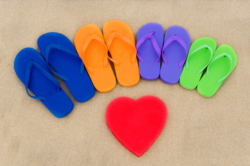 Fototapeta na wymiar Color flip flops and heart on sand
