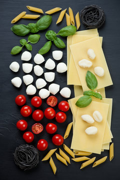 Variety of italian ingredients, black wooden surface, above view