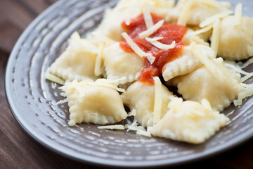 Cheese ravioli with tomato sauce and parmesan topping, close-up