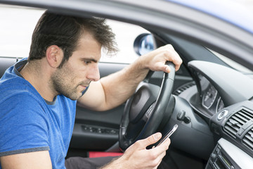 Man driving and looking message in his smart phone.