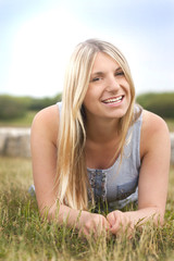 Fototapeta na wymiar Junge blonde Frau im Gras liegend