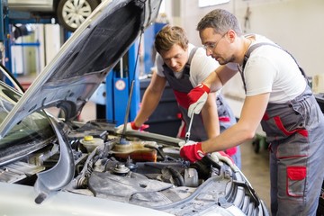 Fototapeta na wymiar Two mechanic fixing car in a workshop