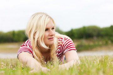 Fototapeta premium Junge blonde Frau im Gras liegend