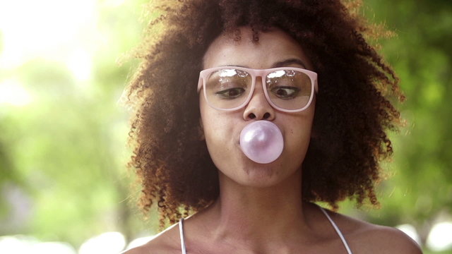 Happy Afro Girl having fun blowing bubble gum in slow motion