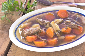 Bowl of vegetable beef soup on wooden background