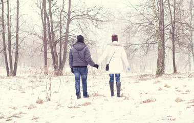 Fototapeta na wymiar Young couple holding hands in the winter park