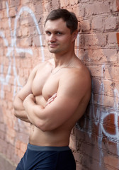 Young athlete bodybuilder man near brick wall