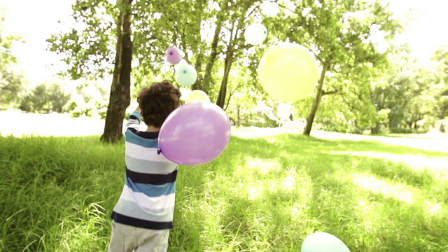 Boy playing with colorful balloons in park