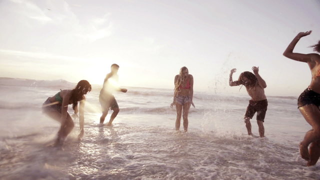 Friends splashing water at the beach