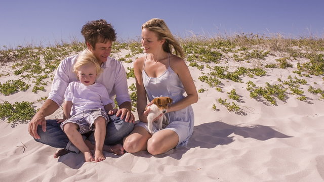 Family and pet dog sitting on beach