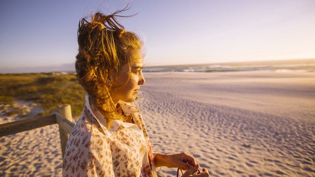 Girl on the bach is looking at sunset