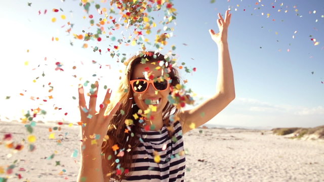 Woman throwing confetti in slow motion on the beach