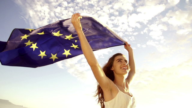 European Woman holding EU flag against sky waving