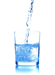 Pouring water into glass on blue background