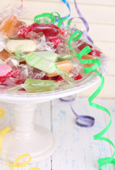 Tasty candies on plate on table on wooden background