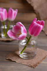 Beautiful tulips in bucket in vase on table on grey background