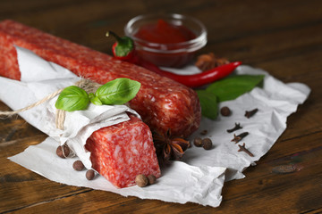 Tasty salami sausage and spices on wooden background