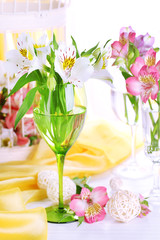 Freesias in glasses on table on fabric background