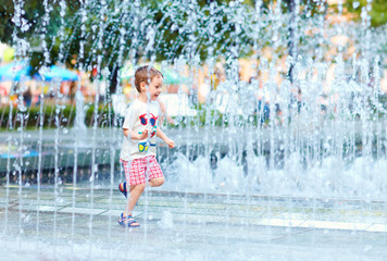 Obraz premium excited boy running between water flow in city park