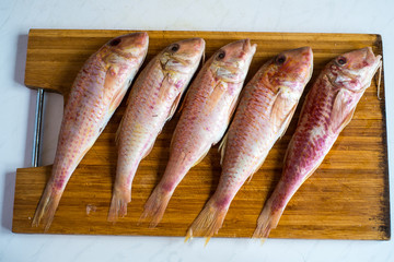 Five raw red fishes on wooden cutting board