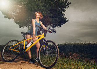 Beautiful athletic girl standing with bike outside the city.