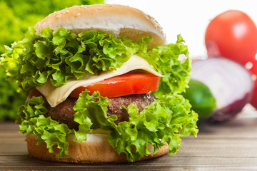 Cheeseburger with lettuce, onions and tomato in a sesame bun