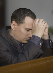 Handsome young man praying in a church