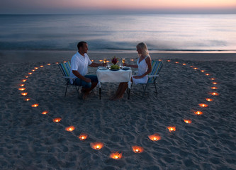 A young couple share a romantic dinner on the beach