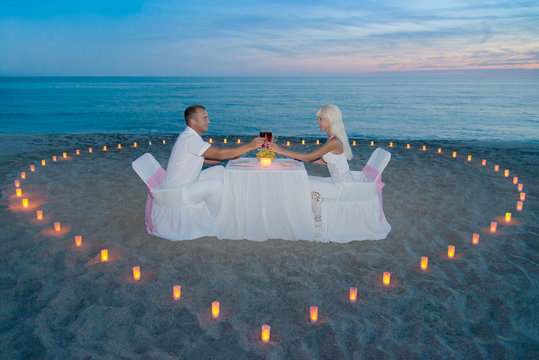 couple at beach romantic dinner with candles heart