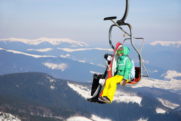 Fototapeta na wymiar Skiers in mountains on a ski-lift