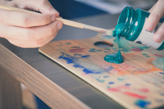 close up hands using paintbrush and colours