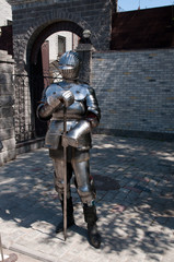 knight in the ancient metal armor standing near the stone wall