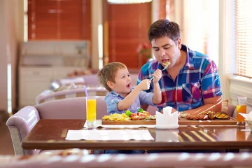 Tableaux ronds sur plexiglas Restaurant boy feeding father in restaurant