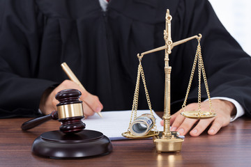 Male Judge Signing Document In Courtroom