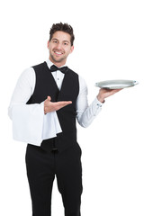Naklejka na ściany i meble Confident Young Waiter With Napkin And Serving Tray