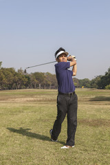Male golfer swinging golf ball