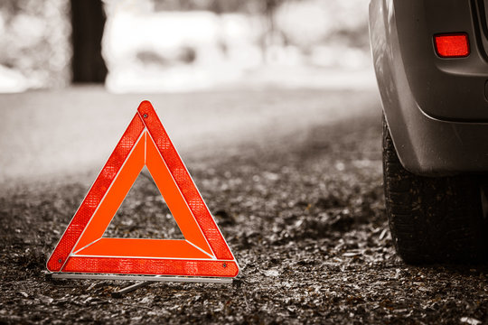Breakdown of car. Red warning triangle sign on road