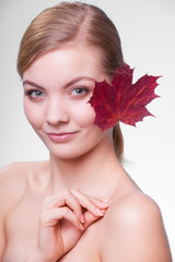 Naklejka na ściany i meble Skin care. Portrait of young woman girl with red maple leaf.