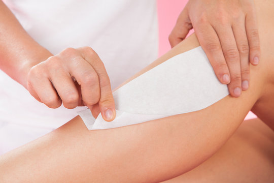 Female Therapist Waxing Customer's Leg At Spa