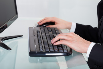 Businessman Using Computer Keyboard At Desk