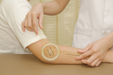 Physiotherapist measuring range of motion patients' elbow with g - obrazy, fototapety, plakaty