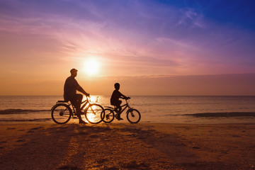 Fototapeta na wymiar father and son at the beach on sunset,Biker family silhouette