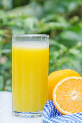 Glass of freshly pressed orange juice with sliced orange  on woo