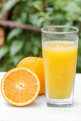 Glass of freshly pressed orange juice with sliced orange  on woo