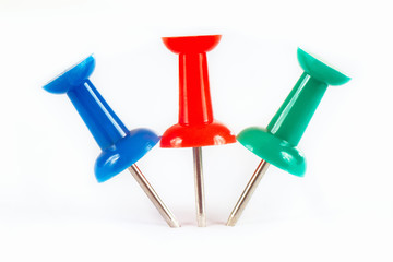 Blue, green and red  pushpins stuck in the white paper close up