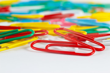 Multicolored office paperclips on white desktop close up