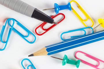 Pencil, pen, paperclip and thumbtack on white desktop